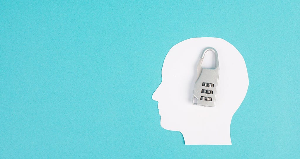 A paper cutout of a head with a combination lock in place of a brain.
